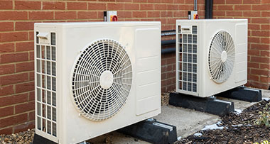air source heat pumps installed outside of a brick property