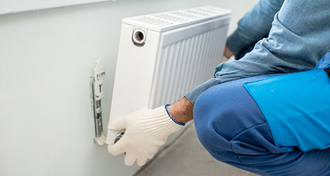 a person installing a radiator onto a wall mount