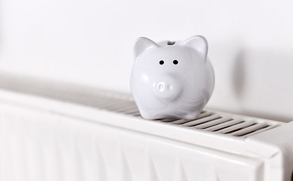 a white piggy bank on top of a white radiator signifying saving money for a power flush
