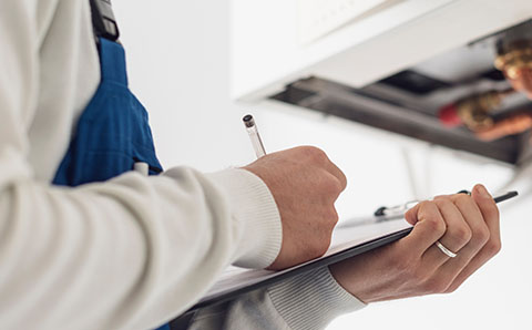 a technician writing on a clipboard for a gas safety inspection