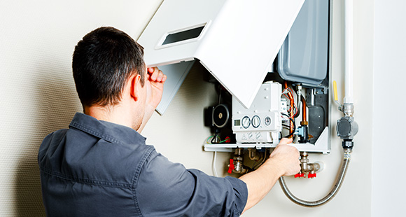 a man lifting the outer casing of a gas boiler to service it