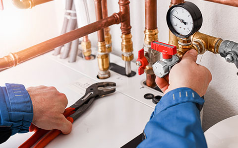 a man installing a boiler pressure gauge with an adjustable wrench