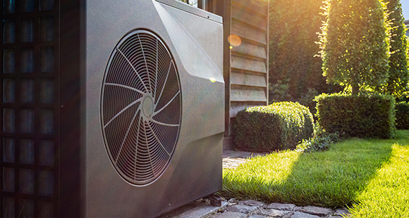 a metal heat pump installed in a garden outside a wooden property